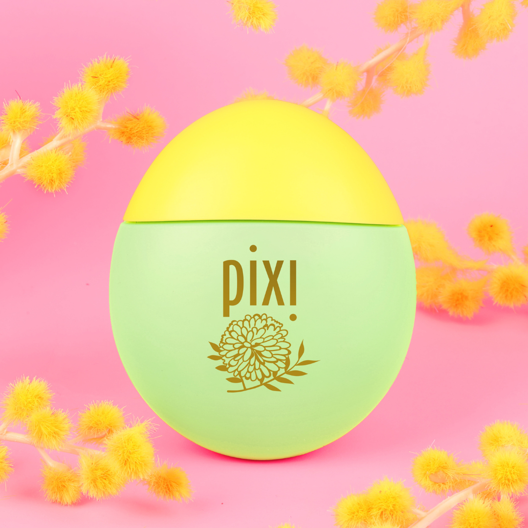 HandHero in PixiMimosa scent shown on a pink background with mimosa blooms
