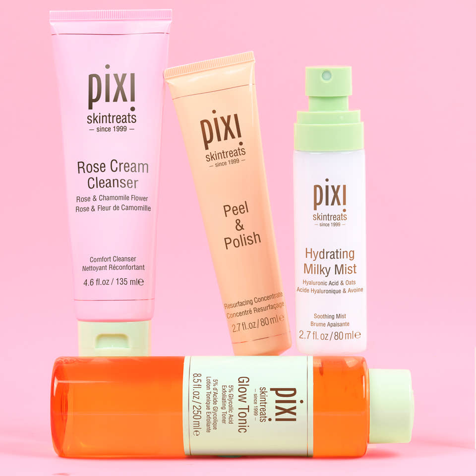 Pixi Glow Starter Routine skincare set arranged on a solid pink background: Rose Cream Cleanser in a pink tube, Peel & Polish in a peach tube, Hydrating Milky Mist in a white bottle with a mint cap, and Glow Tonic in an orange bottle with a pale green cap. view 1