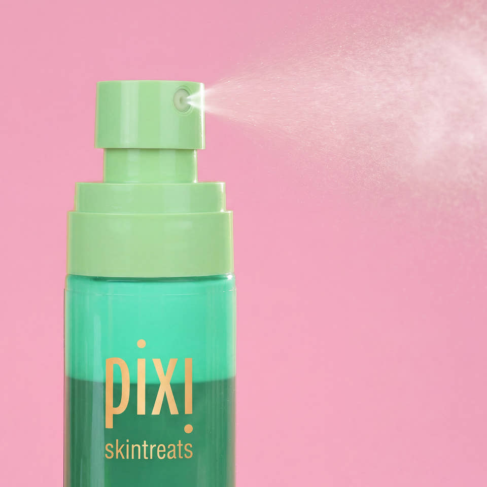 Pixi Skintreats Antioxidant Mist bottle with a light green pump spraying a fine mist against a solid pink background. view 2