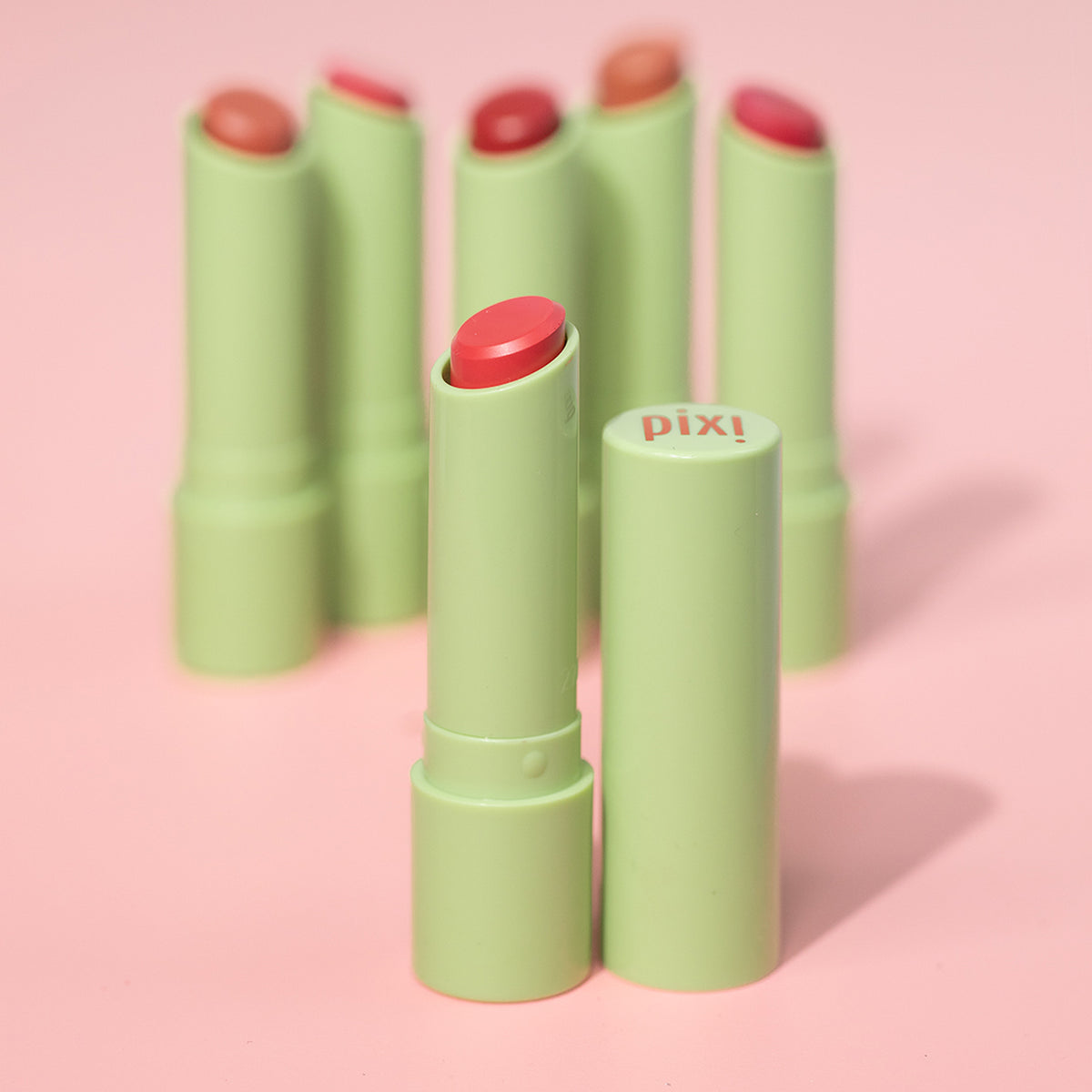 Pixi Naturelle lip balm with pink caps on a pink background