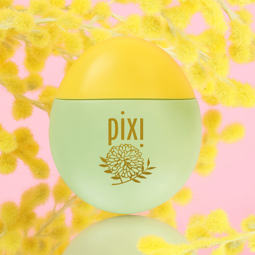 Pixi HandHero PixiMimosa scented hand lotion with mimosa blooms with a light green body and yellow cap, featuring a gold floral logo, set against a pink background with yellow flowers. view 2